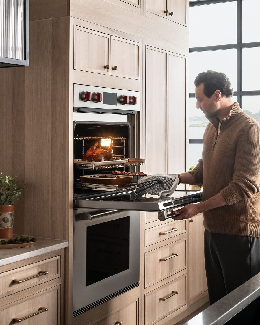 Technician checking a built-in wall oven in a modern kitchen