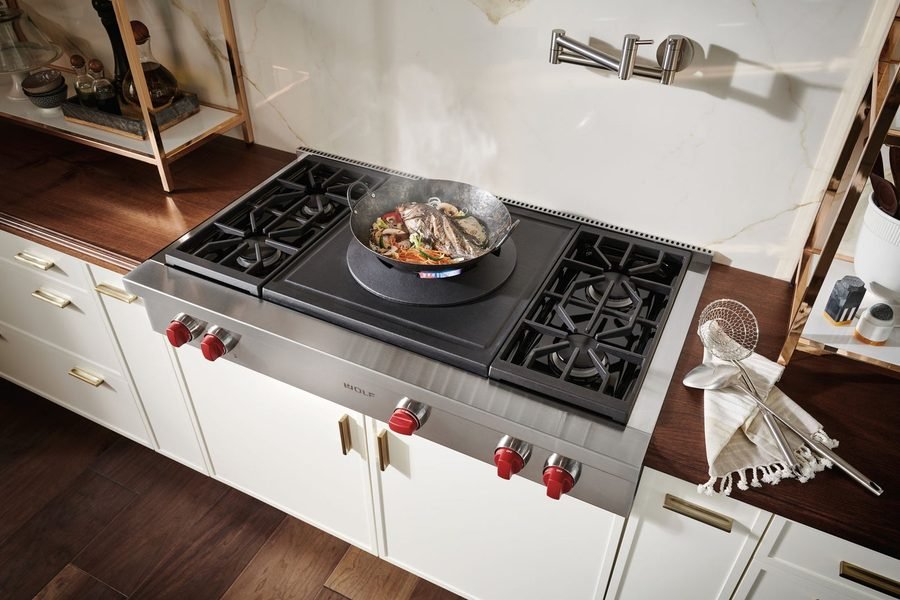 Overhead view of a gas cooktop with a wok cooking vegetables