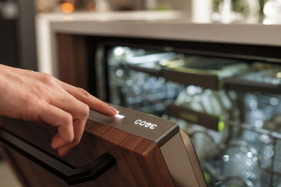 Hand pressing the control panel of a panel-ready dishwasher