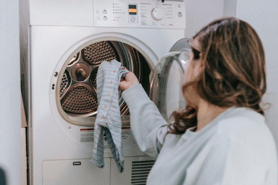 Person unloading laundry from an open front-load clothes dryer