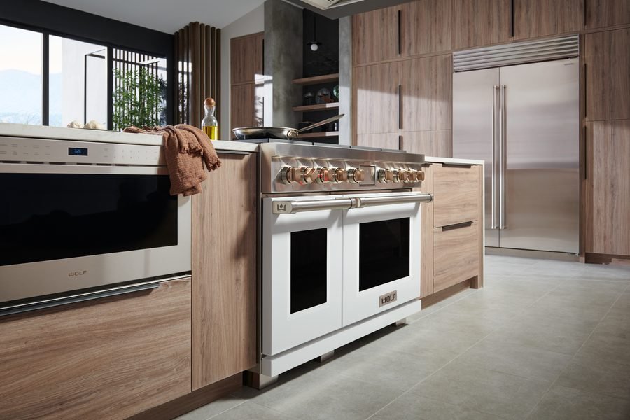 White professional dual-fuel range with brass knobs in a modern kitchen
